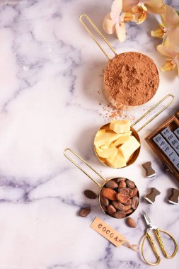 Kakao, kakao yağı ve kakao çekirdekleri, Mermer yüzey üzerinde altın kaplarda çikolata. Düz yatıyordu. Metin için yer.