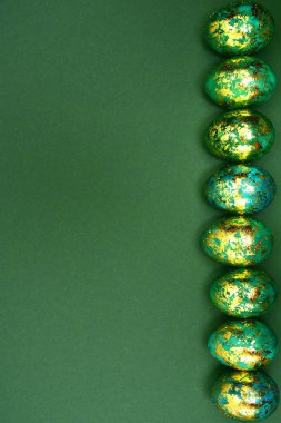 Paskalya yumurtaları, altın yeşil bir arka plan üzerinde koyu yeşil. Yukarıdan görüntüleyin. Düz yatıyordu.