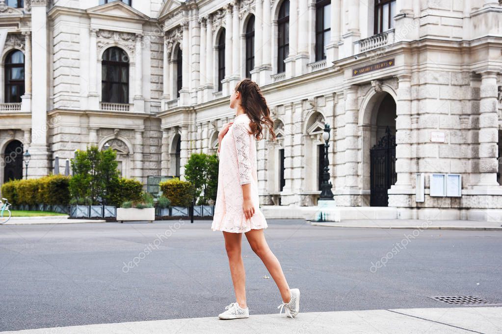 Vienna State Theater Burgtheater, Austria. A girl in a pink dress stands on the background of the building.