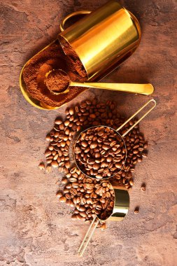 Kahve çekirdekleri, kahverengi arka planda altın fincan kahve.