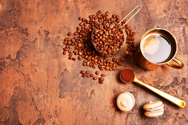 Coffee beans, golden cup of coffee on a brown background.