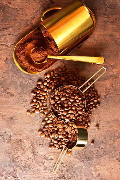 Kahve çekirdekleri, kahverengi arka planda altın fincan kahve.