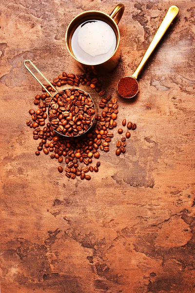 Kahve çekirdekleri, kahverengi arka planda altın fincan kahve.