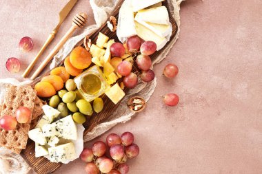 Peynir, bej bir arka planda yer alan bir plakaya yerleştirilir. Peynirler farklı türleri: Camembert, parmesan, mavi peynir, zeytin, bal, üzüm.