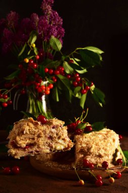 Napolyon pastası ve koyu renk bir arka plan da bir vazo kiraz. Natürmort.