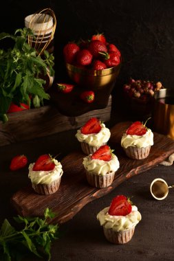 Koyu bir arka plan üzerinde çilek ile Cupcakes. Natürmort