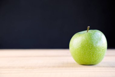 Siyah arkaplanda izole edilmiş yeşil elma, kopya alanı ile ahşap masa üzerinde