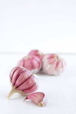 Beyaz ahşap masada birkaç tane taze sarımsak ve fotokopi alanı var.