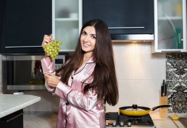 Genç güzel kız mutfakta üzümleri yiyor