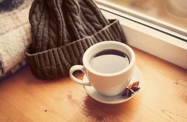 A cup of coffee, a plaid and a hat are on the window. Hello, autumn