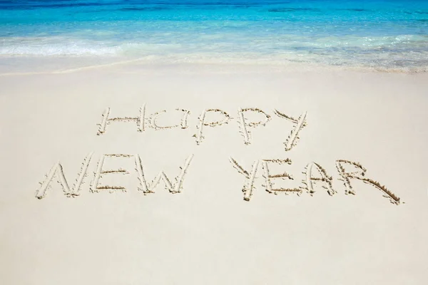 在沙滩上写下的新年快乐。 元旦旅游 免版税图库图片