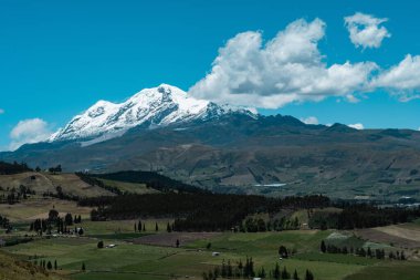 cayambe volkanı ekvatordaki yeşil tarlaların üzerinde güzel mavi bir gökyüzünde 