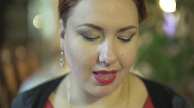 Güzel görünümlü, orta yaşlı, dut yiyen esmer kadının şık bir restoranda kameraya bakıp gülümsemesinin keyfini çıkarın.