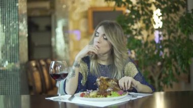 Genç, çekici, sarışın kız şık bir restoranda yağlı parmaklarını yalıyor toplum içinde uygunsuz davranışlar sergiliyor.