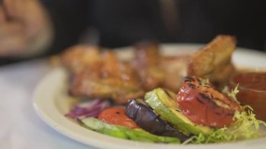 Erkek eli bıçak çatalıyla yakın. Lezzetli ızgara sebzeli kızarmış tavuk eti. Lüks bir restoranda.