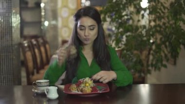 Çekici genç esmer kız kremalı pastadan büyük bir porsiyon yiyor ve elleri kirli.