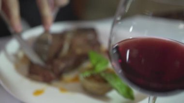 Yakışıklı, esmer, mavi gözlere odaksız bir bakış at. Biftek kesen genç adam kırmızı şarabın tadını çıkarıyor.