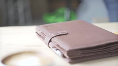 Zarif not defteri kurşun günlük alışkanlığı takip cihazı açık kahverengi deri çanta tutacağı ahşap masa üzerinde tablet