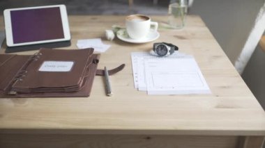 Çalışma alanı masaüstü ahşap masasının tablet cep telefonu ile görüntülenmesi. Bir fincan sıcak içecek keather çanta not defteri.