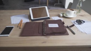 Çalışma masası masaüstünün tablet cep telefonlu görüntüsü. Bir fincan sıcak kahve, çay ve deri defter defteri.