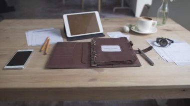 Çalışma alanı masaüstü, tablet cep telefonu kahve fincanı deri saat defteri ile güzel bir yakın çekim görüntüsü.