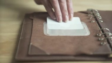 Kadın eli zarif açık kahverengi deri çanta kullanıyor günlük planlama alışkanlığı takip defteri ahşap masa üzerinde yakın plan