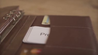 İş organizatörünün yakın plan çekimi günlük günlük günlük not defteri açık kahverengi deri çanta ahşap masa üzerinde