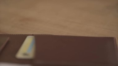 Organizatörün yakın plan günlük not defterini yakın çekimde, açık kahverengi deri kart tutacağıyla ahşap masanın üzerinde.