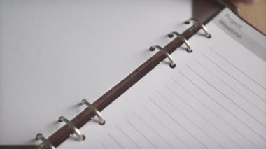 Kadın elinin deri kapakta metal klasörü açtığı yakın plan günlük organizatör not defteri defteri.