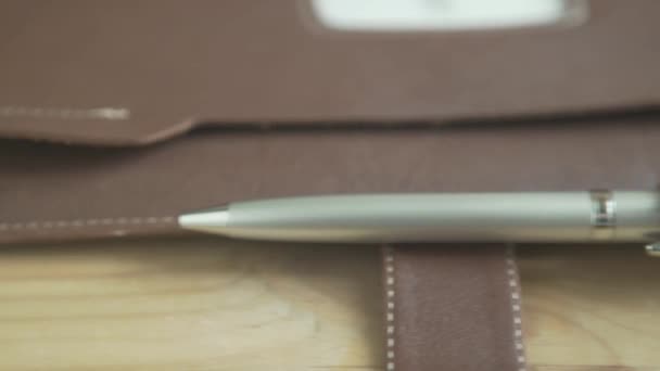 木制写字台上印有银笔架的浅褐色皮盒记事本日记本的精美近照 — 图库视频影像