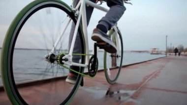 Bulutlu bir günde, sakin bir akşam nehrinin yanında bisiklet süren genç bir erkek.