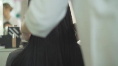 Moda salonuna dokunan profesyonel bayan kuaförün ellerinde zıplayan düz siyah saçlar.