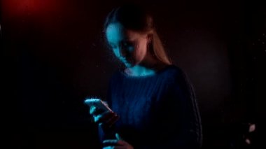 Genç üzgün, rüya gibi çekici kadın buharlı yağmur damlası penceresinin arkasında oturuyor ve akıllı bir telefon görüşmesi yapıyor.
