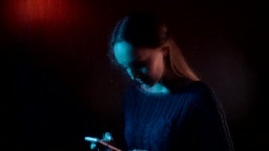 Genç, hayalperest, üzgün, çekici kadın buharlı yağmur damlası penceresinin arkasında oturmuş, akıllı bir telefon konuşması yapıyor.