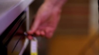 Erkek veznedarın kasiyer çekmecesini anahtarla açarken çekilen yakın çekim para banknotlarını hızlıca alırken.