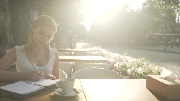 Loira Jovem Sexo Feminino Vestido Branco Mesa Terraço Café Escrevendo — Vídeo de Stock