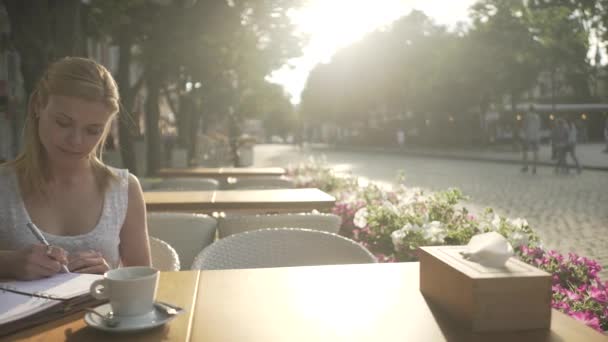 Menina Loira Jovem Vestido Branco Mesa Terraço Café Fora Escrevendo — Vídeo de Stock