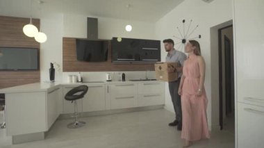 Yeni moda, modern bir daireye taşınan mutlu ve heyecanlı genç çift 4K 'lık çekimde güzel iç tasarımı inceliyor.