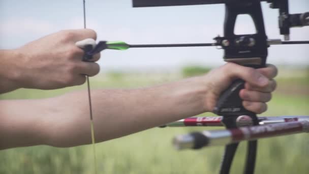 中年男子弓箭手双手弯曲机械弓箭集中射向目标绿地的近景射击 — 图库视频影像