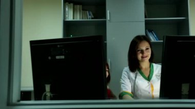 Profesyonel çekici bayan doktor gülümsüyor. Ofisteki küçük tatlı kıza bilgisayar ekranını gösteriyor.