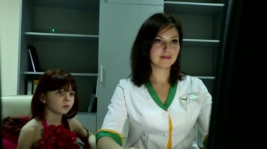 Genç, çekici, profesyonel doktor gülümseyen, ofisteki sevimli, mutlu kıza bilgisayar ekranını gösteren.