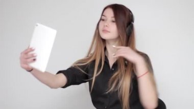 Güzel genç bayan kulaklıkla müzik dinliyor ve tabletle fotoğraf çekiyor.