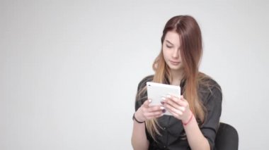 Genç ve güzel bir kadın beyaz tablet kullanıyor ve arka planda saç düzeltiyor.