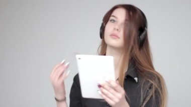 Telsiz kulaklıkla müzik dinleyen güzel genç kız fotoğraf tableti çekiyor.