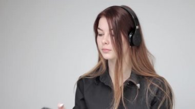 Genç, güzel, kablosuz kulaklıklı kadın fotoğraf çekmek için tablet ve telefon kullanıyor.