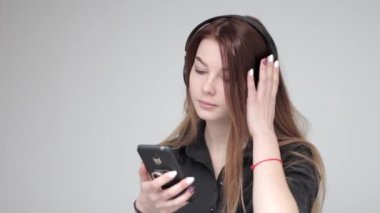 Siyah kablosuz kulaklıklı genç bayan akıllı telefon kullanıyor.