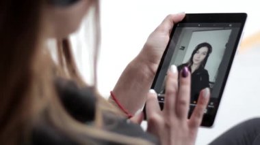 Fotoğraflarını düzenleyen güzel bir genç kadın tablet üzerinde filtre efektleri uyguluyor.