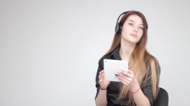 Genç mutlu güzel kız beyaz tablet poz veriyor ve akıllı telefondan fotoğraf çekiyor.