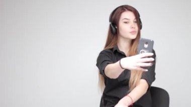 Kablosuz kulaklıklı güzel bir kadın akıllı telefondan fotoğraf çekiyor.