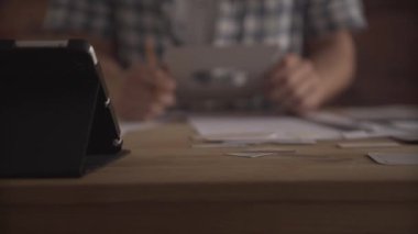 Adam eli dikkatle çalışıyor. Tahta masa üzerinde kağıt işi projesinin küçük detaylarına odaklanmış.